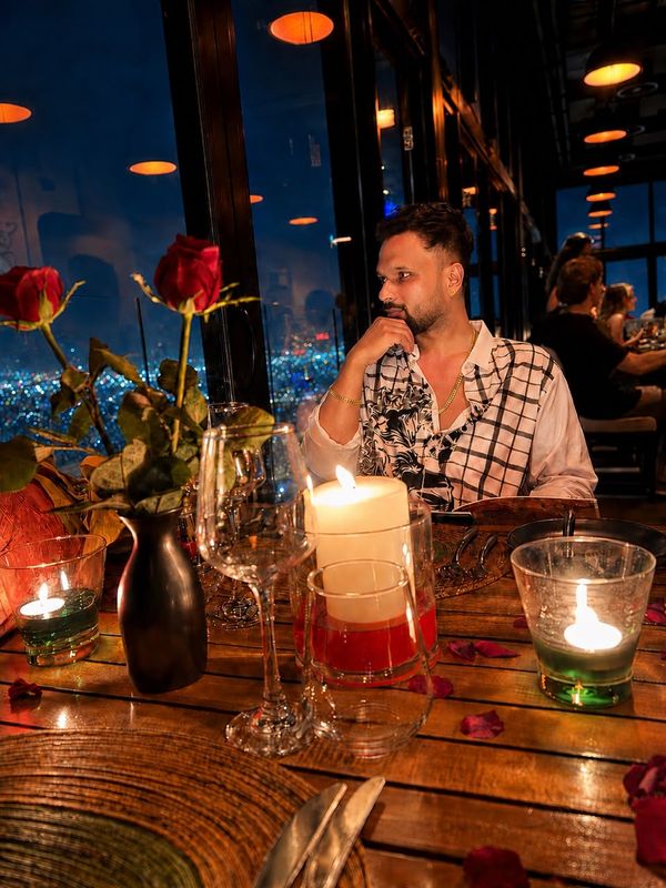 Heshan at a candlelit rooftop table.
